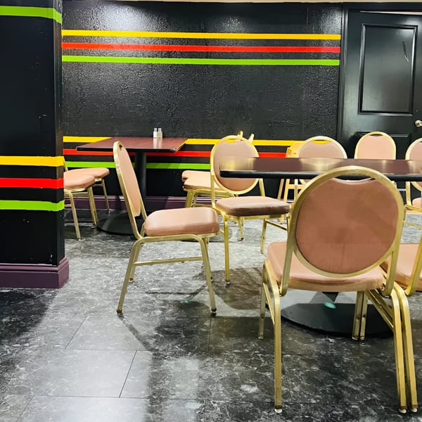 Dining area with black walls, colorful stripes, dark tables, and gold-framed chairs at Haveli Grill.