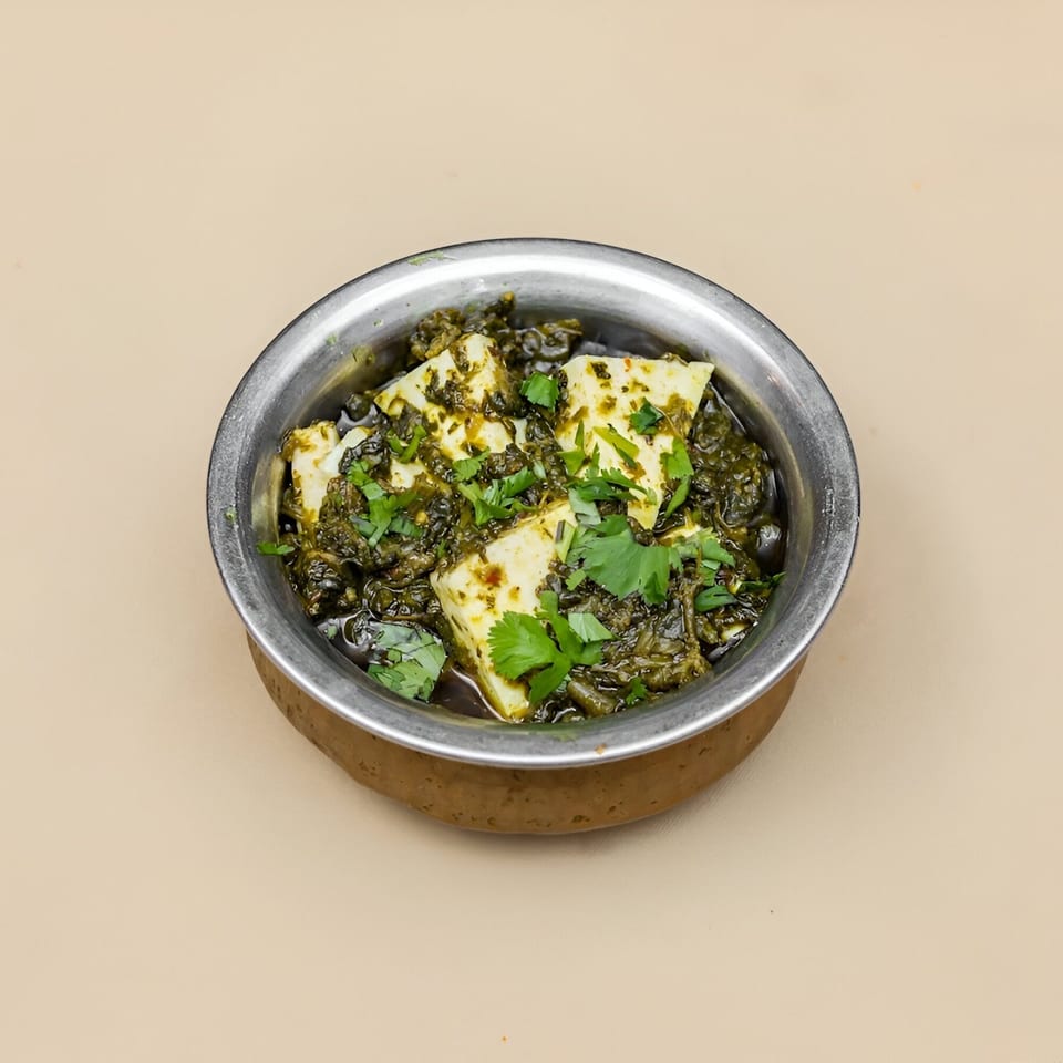 Palak Paneer, a Pakistani dish with spinach and cheese, in a metal bowl.