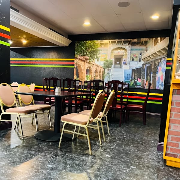 Interior of Haveli Grill with tables, chairs, and a large mural of an ornate building.
