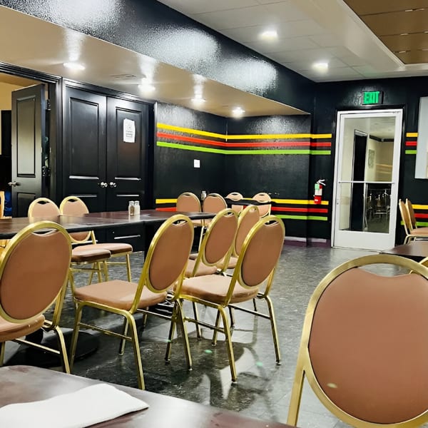 Empty dining room with black walls, colorful stripes, brown tables, and gold-framed chairs at Haveli Grill.